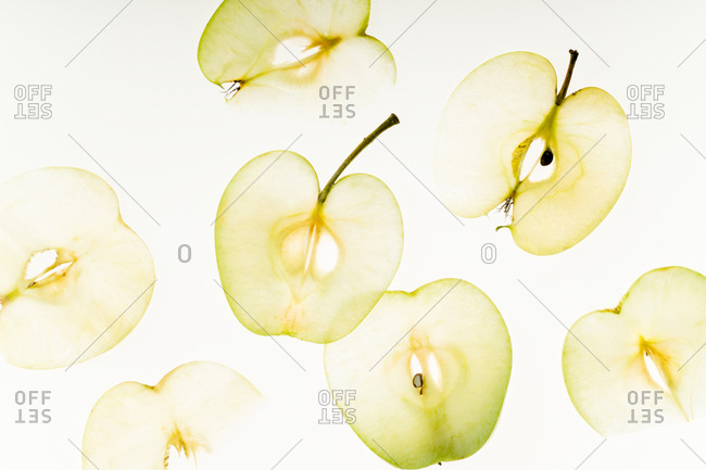 Minimalistic composition with fresh apples sliced and backlit on white background