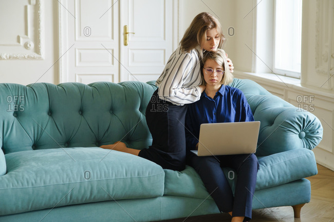 Lesbian couple spend their time together at home working at the laptop and watching partner's work