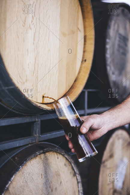 Cropped hand of brewer filling beer from barrel at warehouse