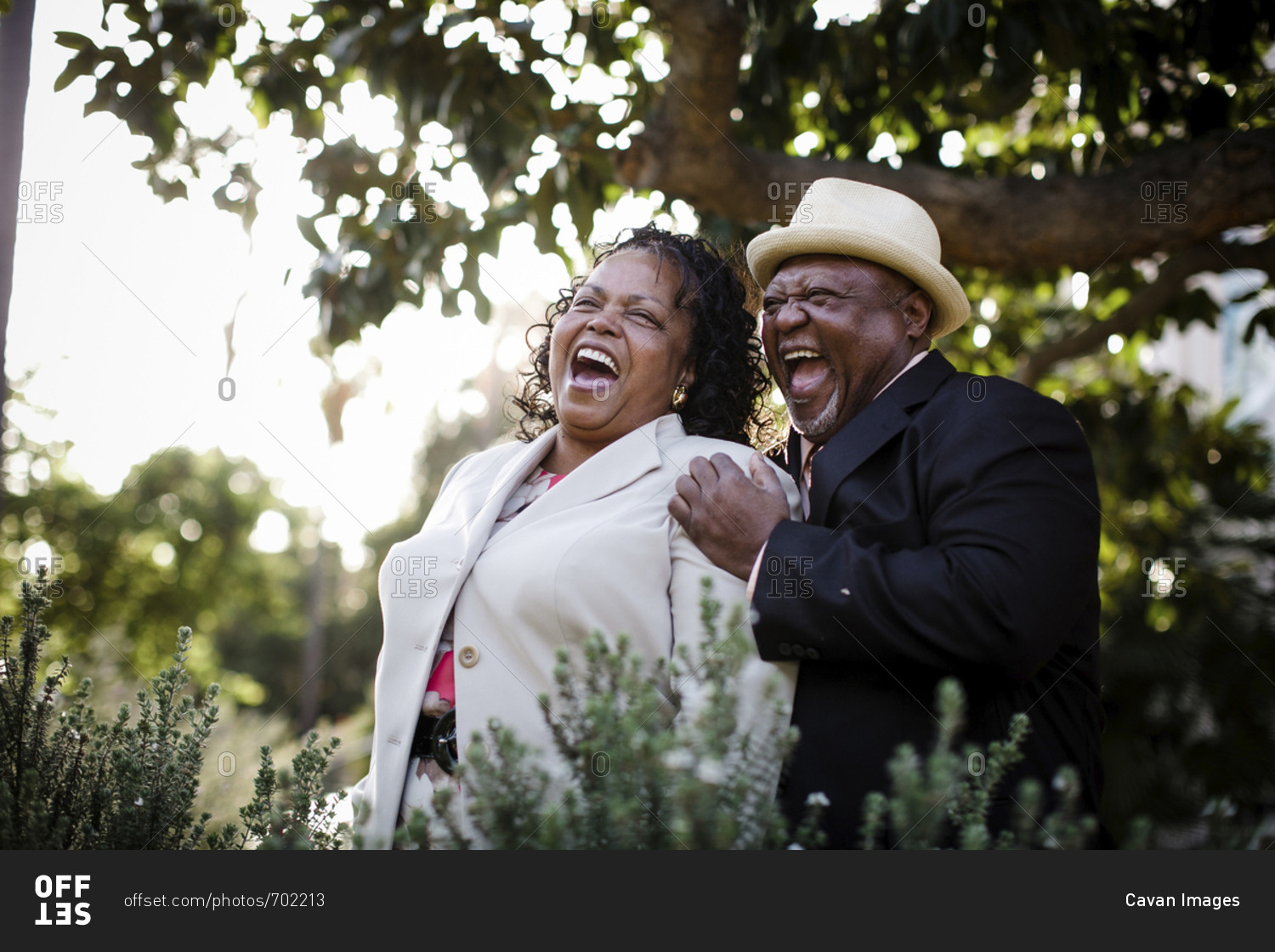 Happy senior couple laughing while standing at park