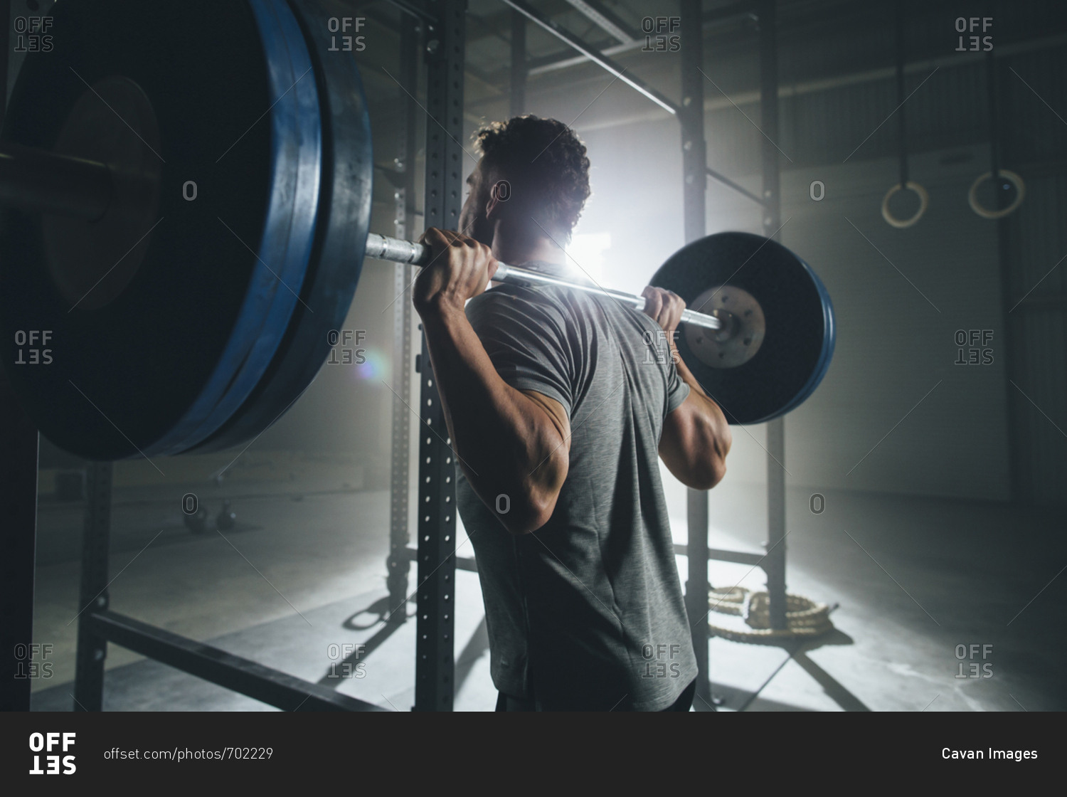 Side view of male athlete lifting barbell at health club