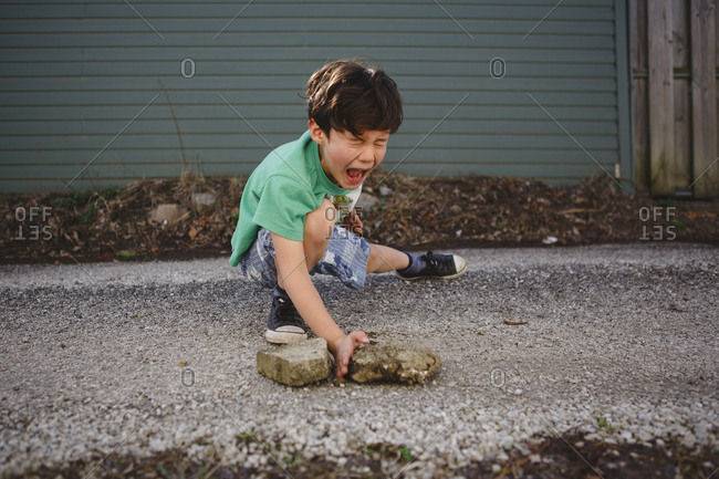 Boy imitating to break stones while practicing karate on street