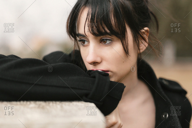 Melancholic woman in black leaning on fence