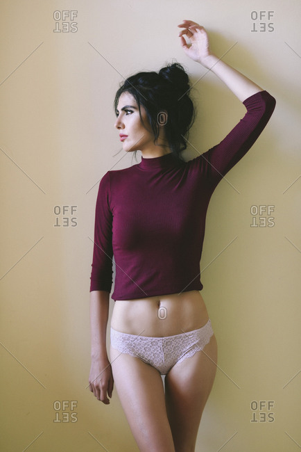 Woman poses near a window wearing purple sweater and panties stock