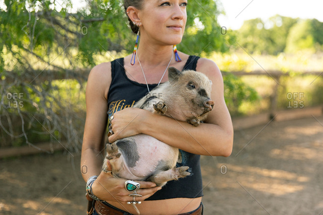 Young woman holding spotted baby pig