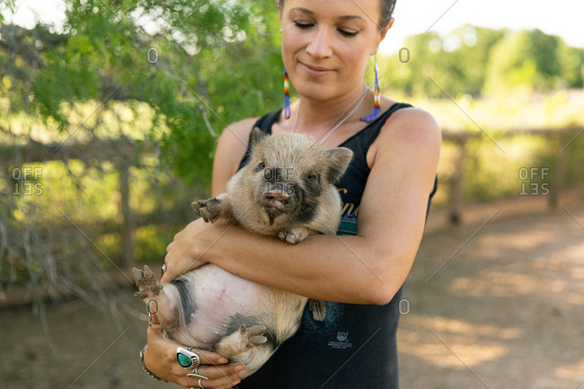 Woman holding spotted baby pig