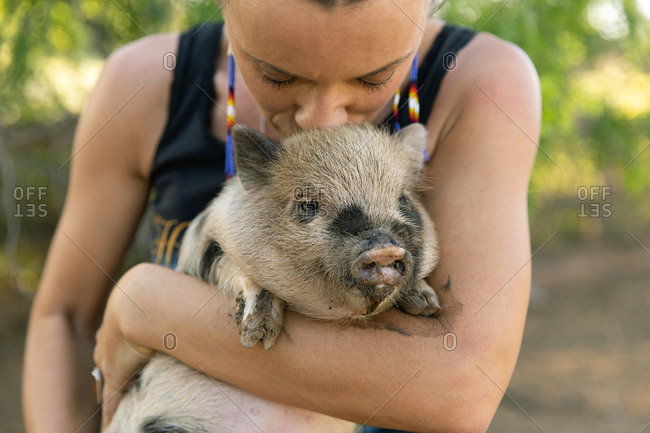 Woman holding and kissing a spotted baby pig