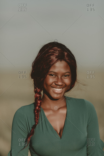 Outdoor portrait of smiling woman with braided hair and facial piercing
