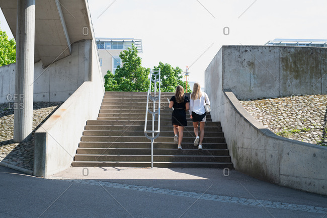 Back view of two women walking up outdoor steps