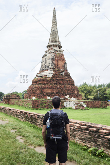 Backpacker contemplating an ancient building in Ayutthaya ruins, Thailand