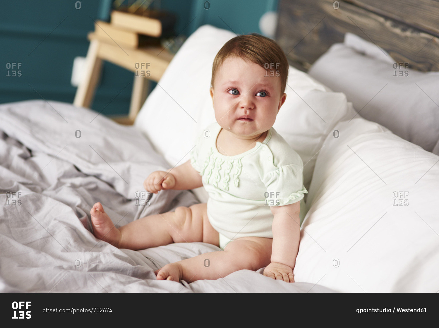 Sad baby crying on bed at home