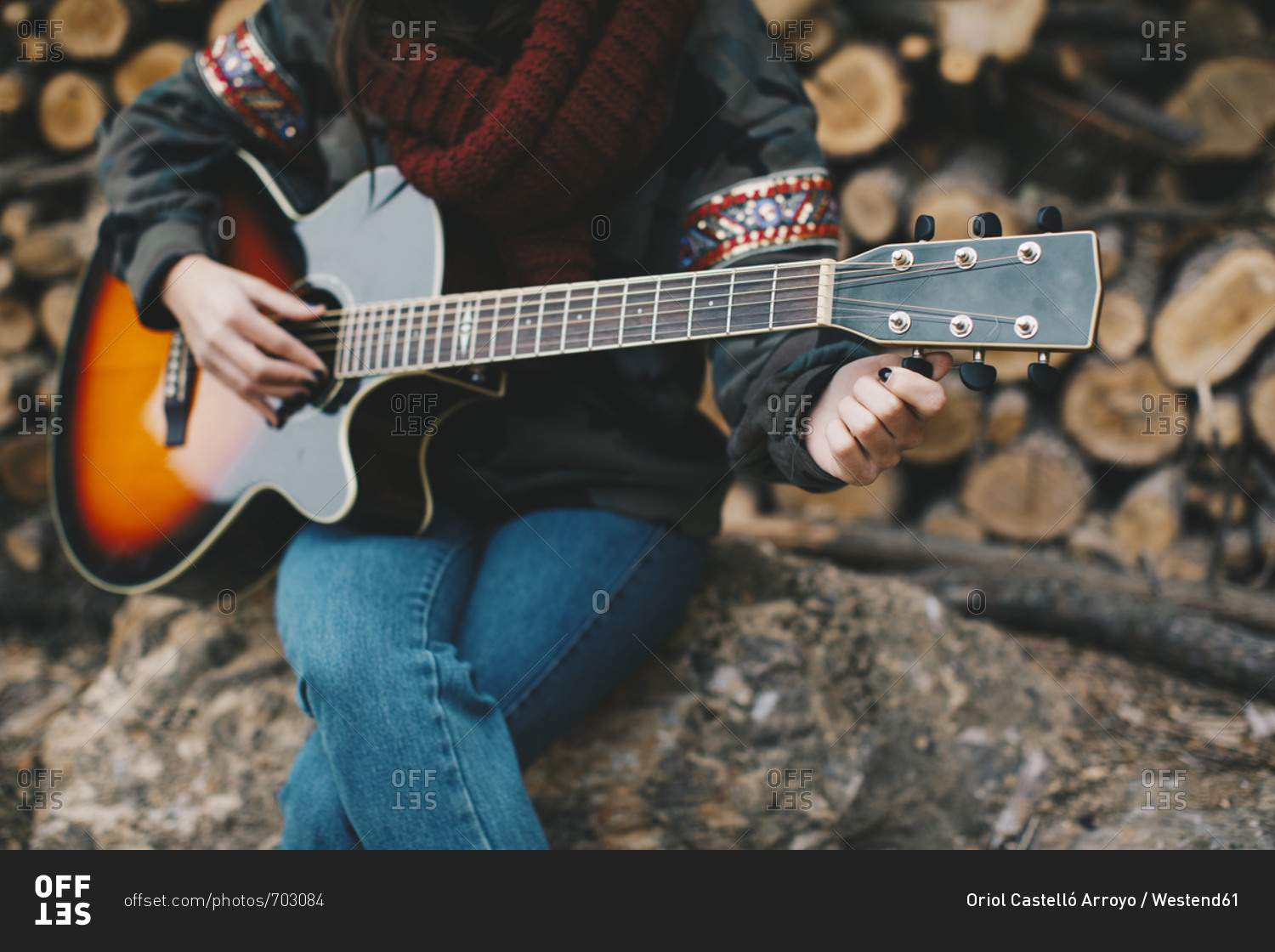 Young woman tuning guitar outdoors- partial view