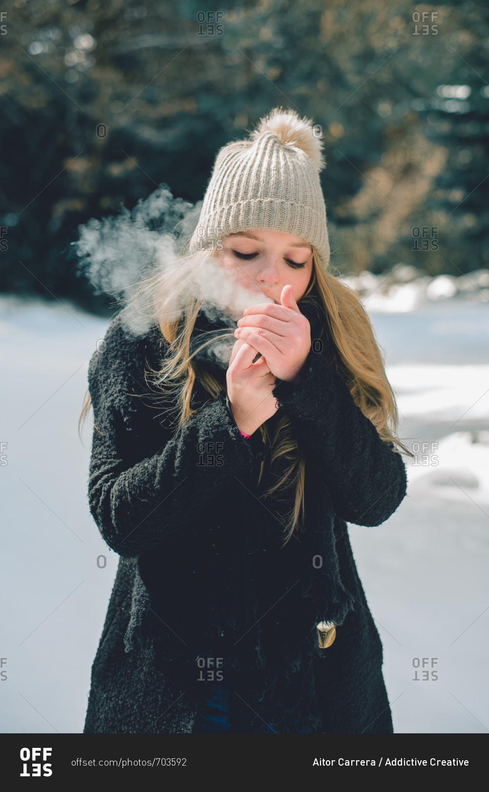 Pretty woman standing and smoking up cigarette in winter nature