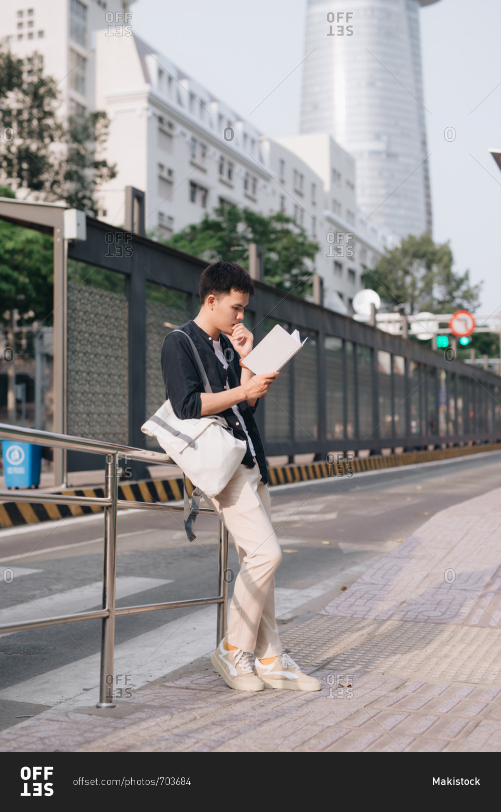 Young asian man was reading book while waiting for a public bus