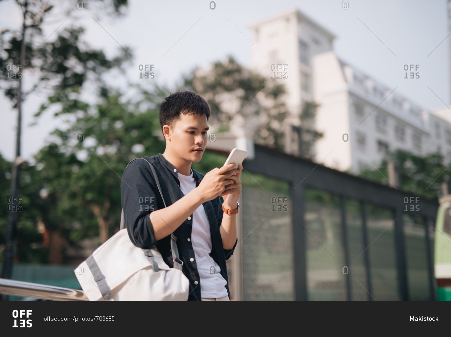 Portrait of asian man texting while waiting for a public bus