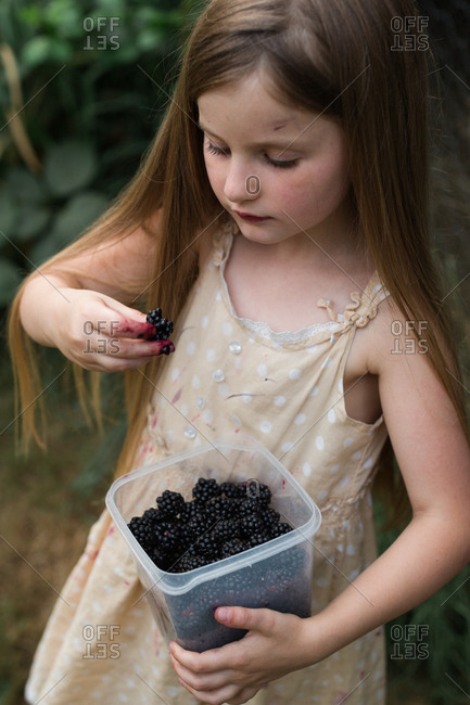 Young girl holding container of fresh picked blackberries
