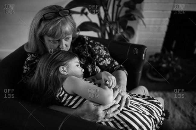 Grandmother cuddling with little girl in chair