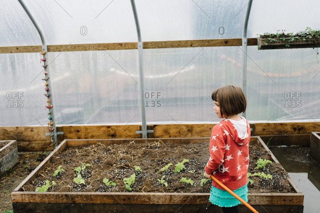 Girl watering plants in greenhouse