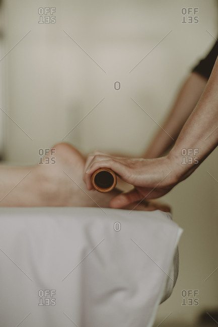 Side on view of woman receiving roller massage on soles of feet