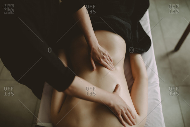 Overhead view of massage therapist working on female client's back
