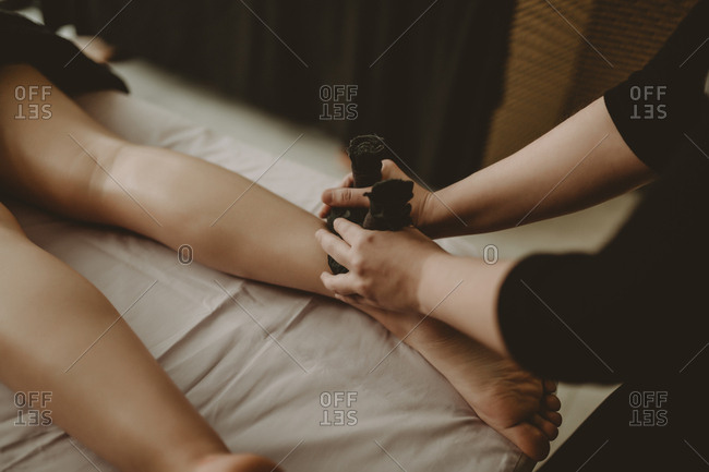 Woman receiving treatment on lower legs from massage therapist in spa