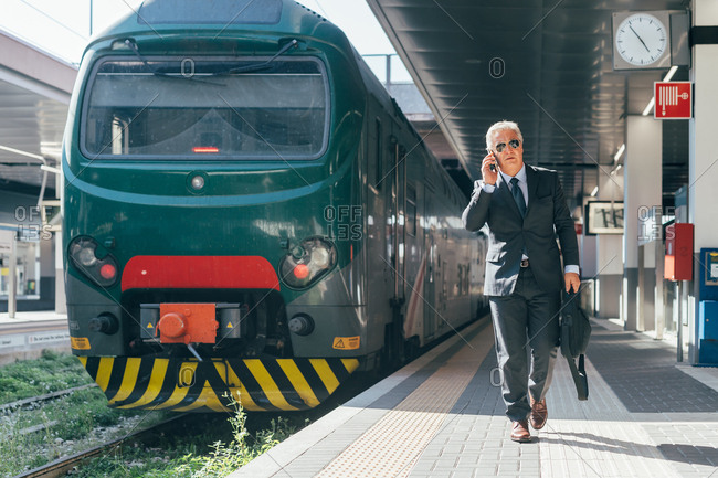 Middle-age businessman talking on a smart phone in a railway station