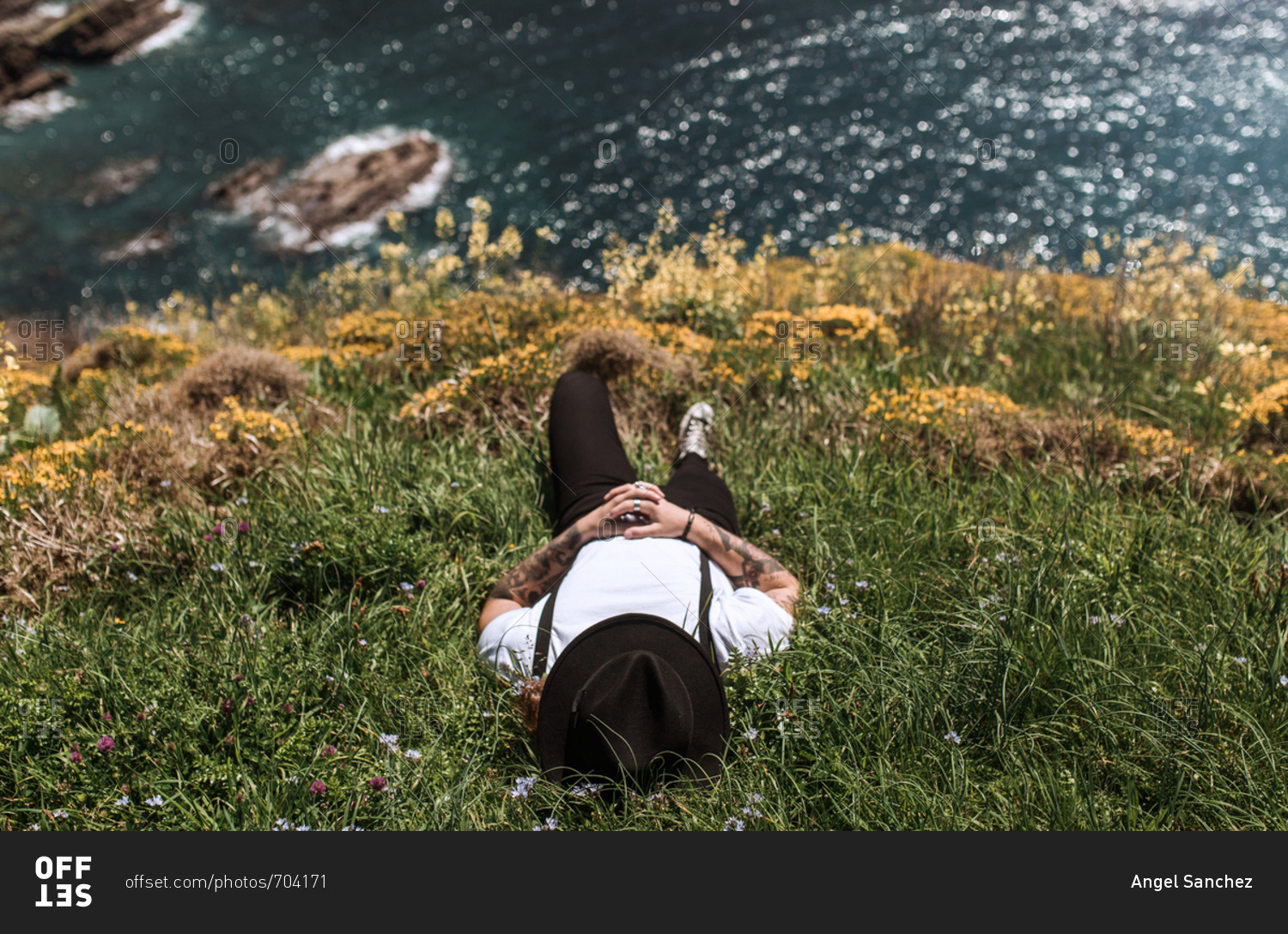 A young vintage man relaxes lying on an island in the middle of the flowers and glass