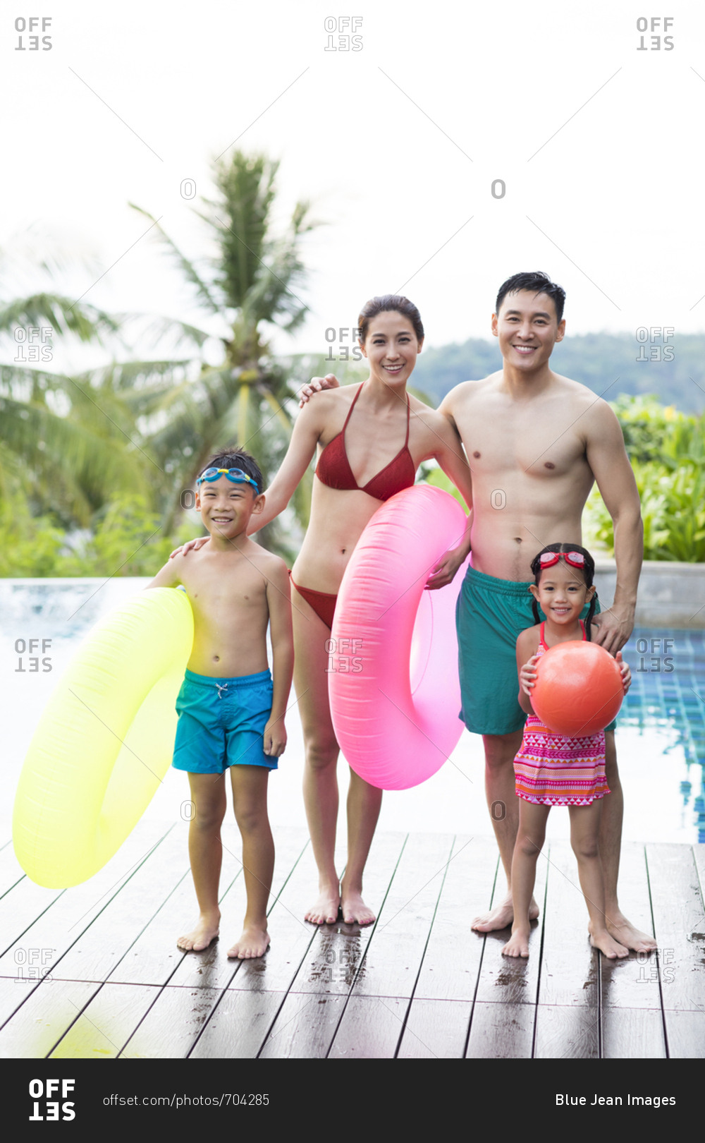 Happy young Chinese family with swimming tubes