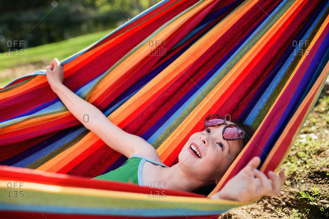 Little girl stretching out in striped multicolor hammock