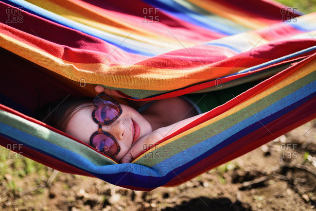 Playful little girl peering out of multicolor hammock