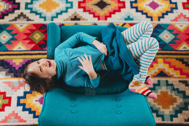 Overhead view of young girl on chair over brightly colored rug