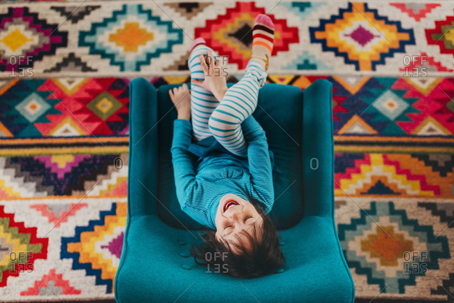 Upside down top view of excited brunette girl sitting in chair