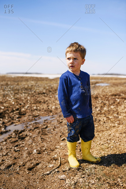 A  young boy playing in mud puddles in a field