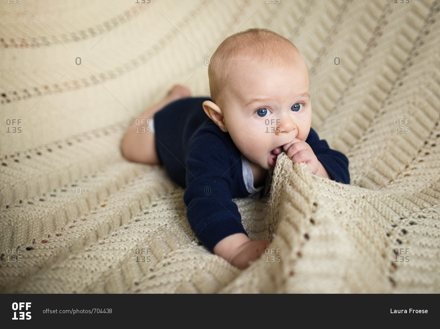 Baby chewing on a knitted blanket