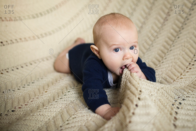 Baby chewing on a knitted blanket