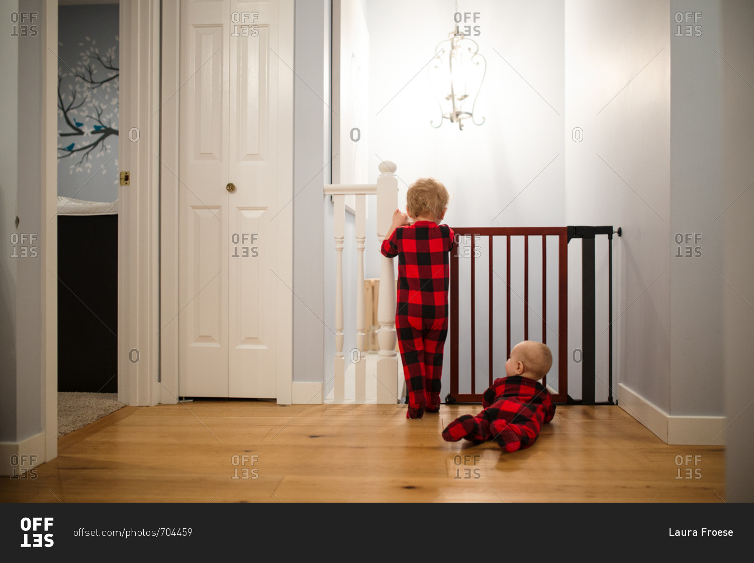 Toddler and baby wearing matching pajamas looking through gate