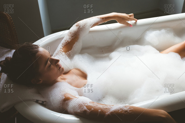 Woman taking a bubble bath in bathroom at home stock photo - OFFSET