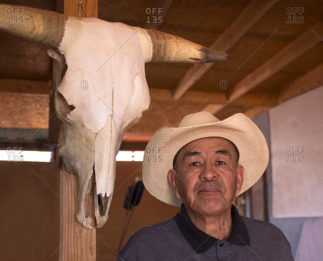 Monument Valley, Utah, USA - May 6, 2018: Portrait of a Navajo man standing next to a cow skull