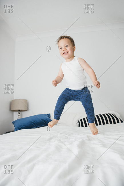 Smiling toddler jumps on bed