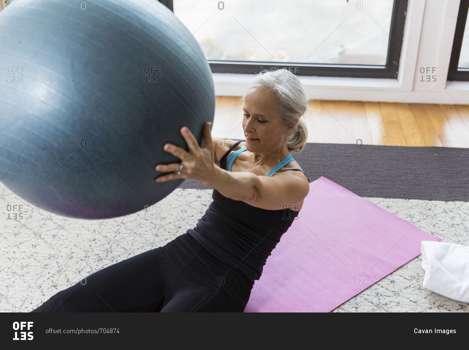 Senior woman holding fitness ball while exercising at home