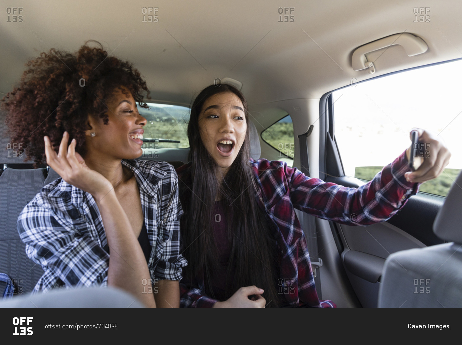 Happy female friends talking selfie while traveling in car
