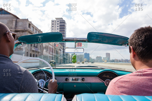 Havana, Cuba - November 19, 2016: Men riding in the front seat of a convertible down the Malecon