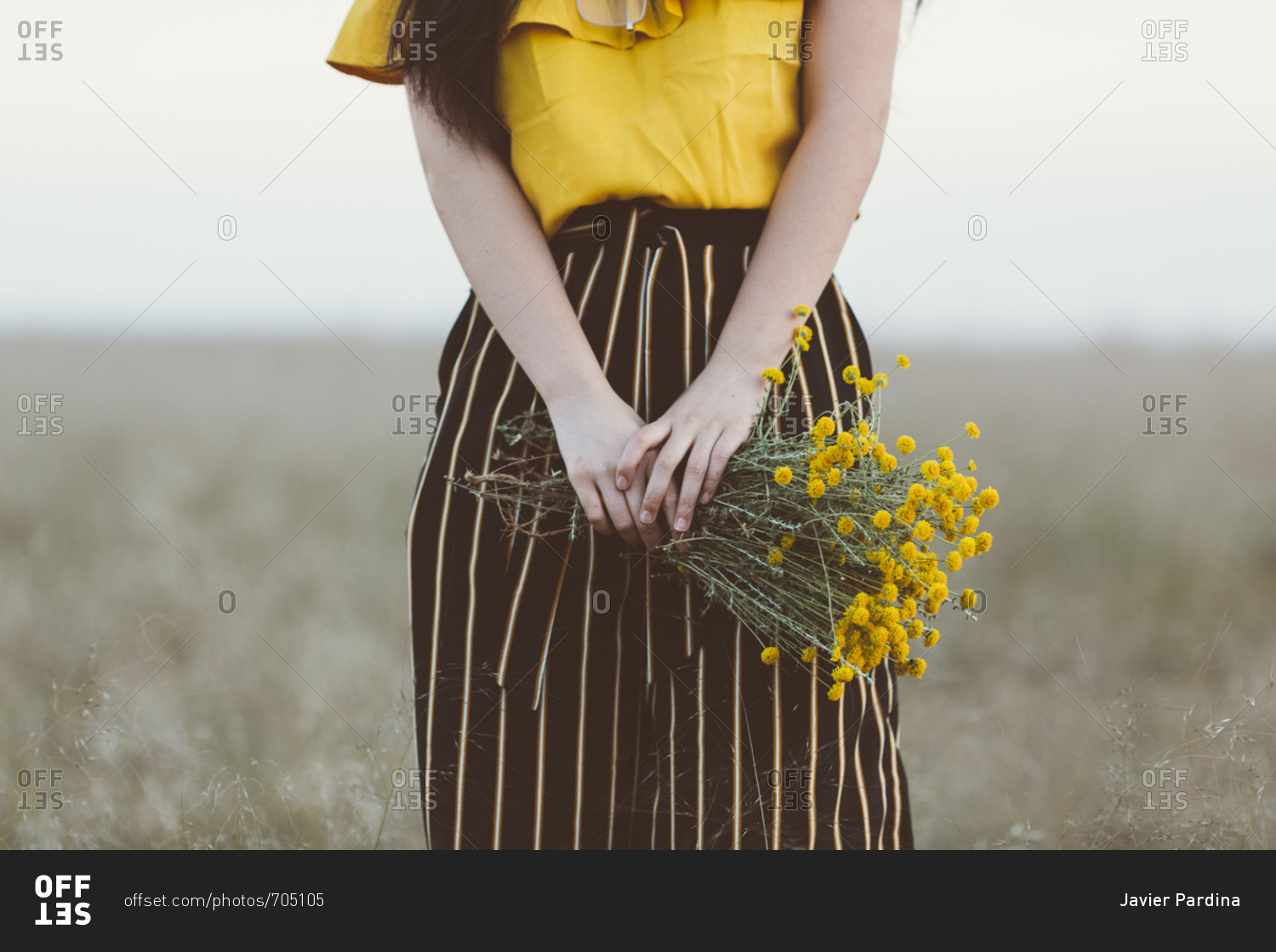 Woman in field holding yellow flowers