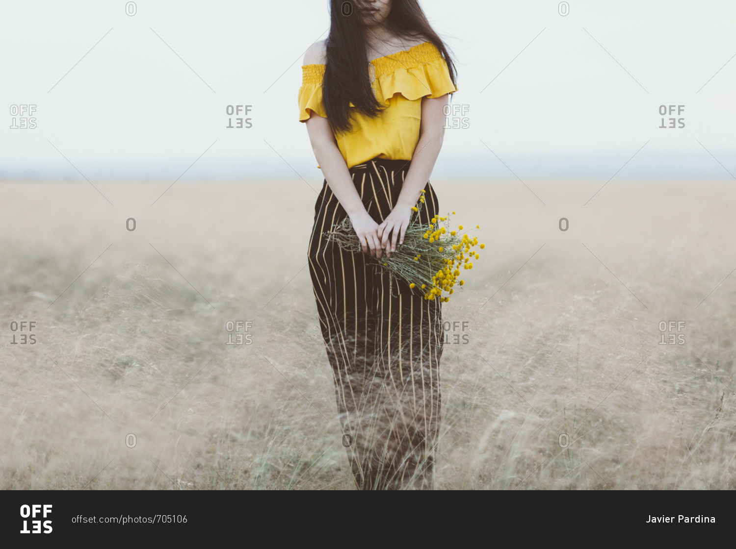 Young Asian woman in field holding yellow flowers
