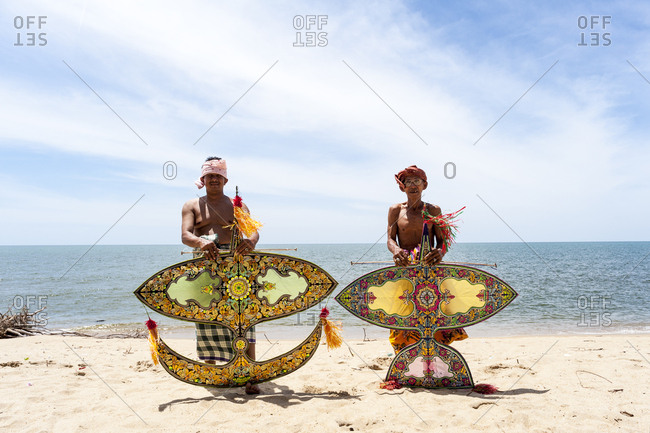 Khota Bharu, Malaysia - July 10, 2012: Two shirtless men holding kites on beach