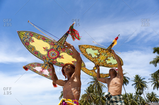 Khota Bharu, Malaysia - July 10, 2012: Low angle view of two men preparing to fly kites