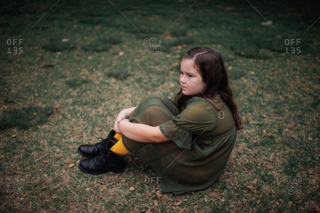 Young girl sitting on lawn in textured sheer dress