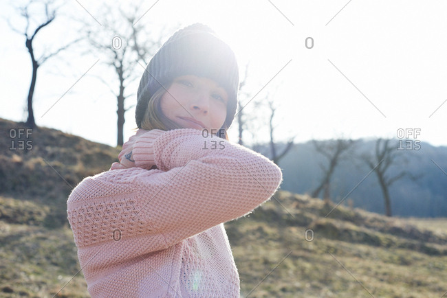 Sunlit portrait of mid adult woman wearing knitted hat in field