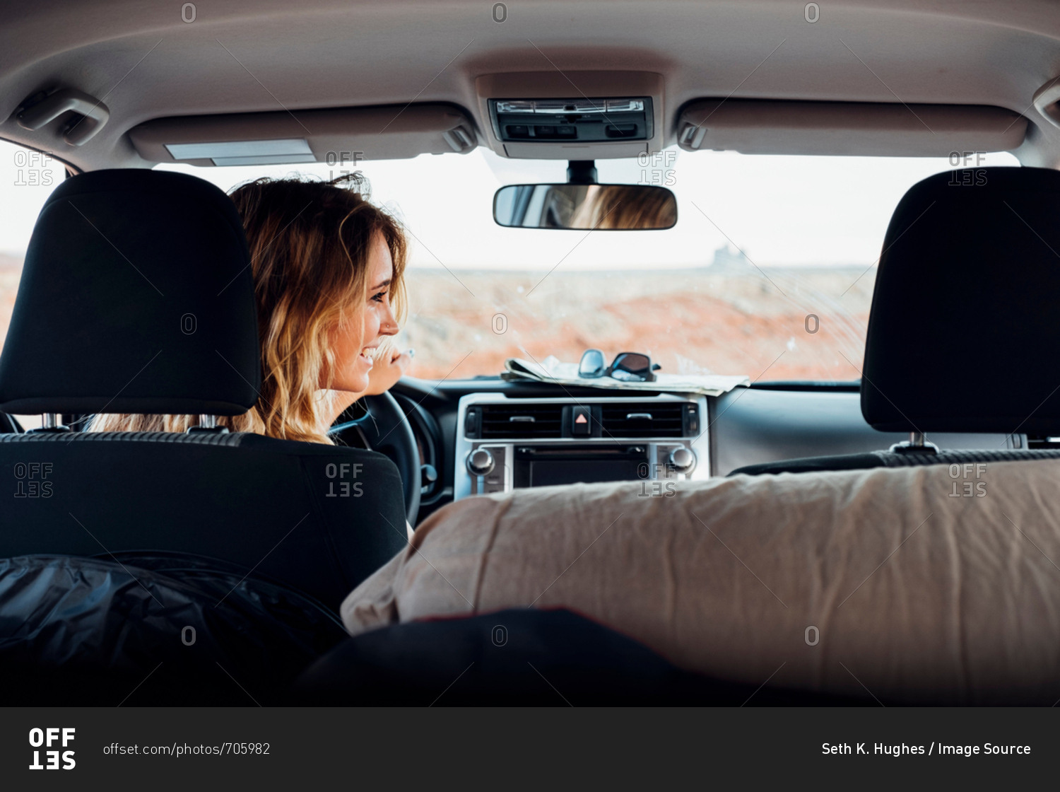 Young woman driving vehicle in remote setting, rear view, vehicle interior, Mexican Hat, Utah, USA
