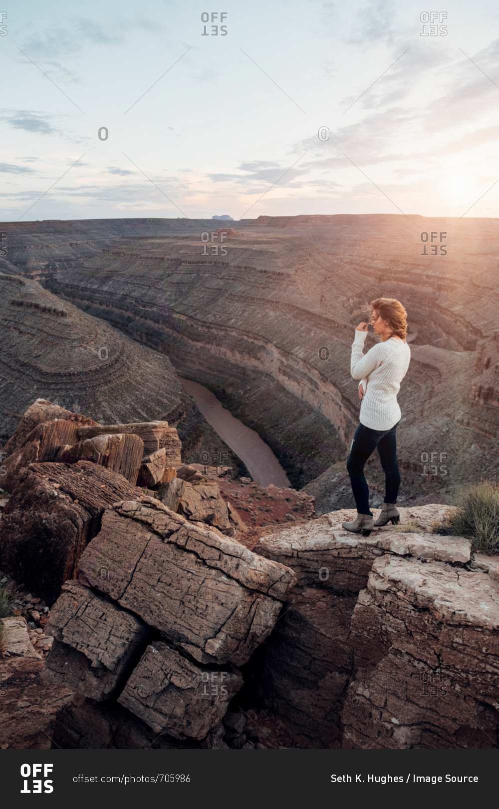 Young woman in remote setting, standing on rocks, looking at view, Mexican Hat, Utah, USA